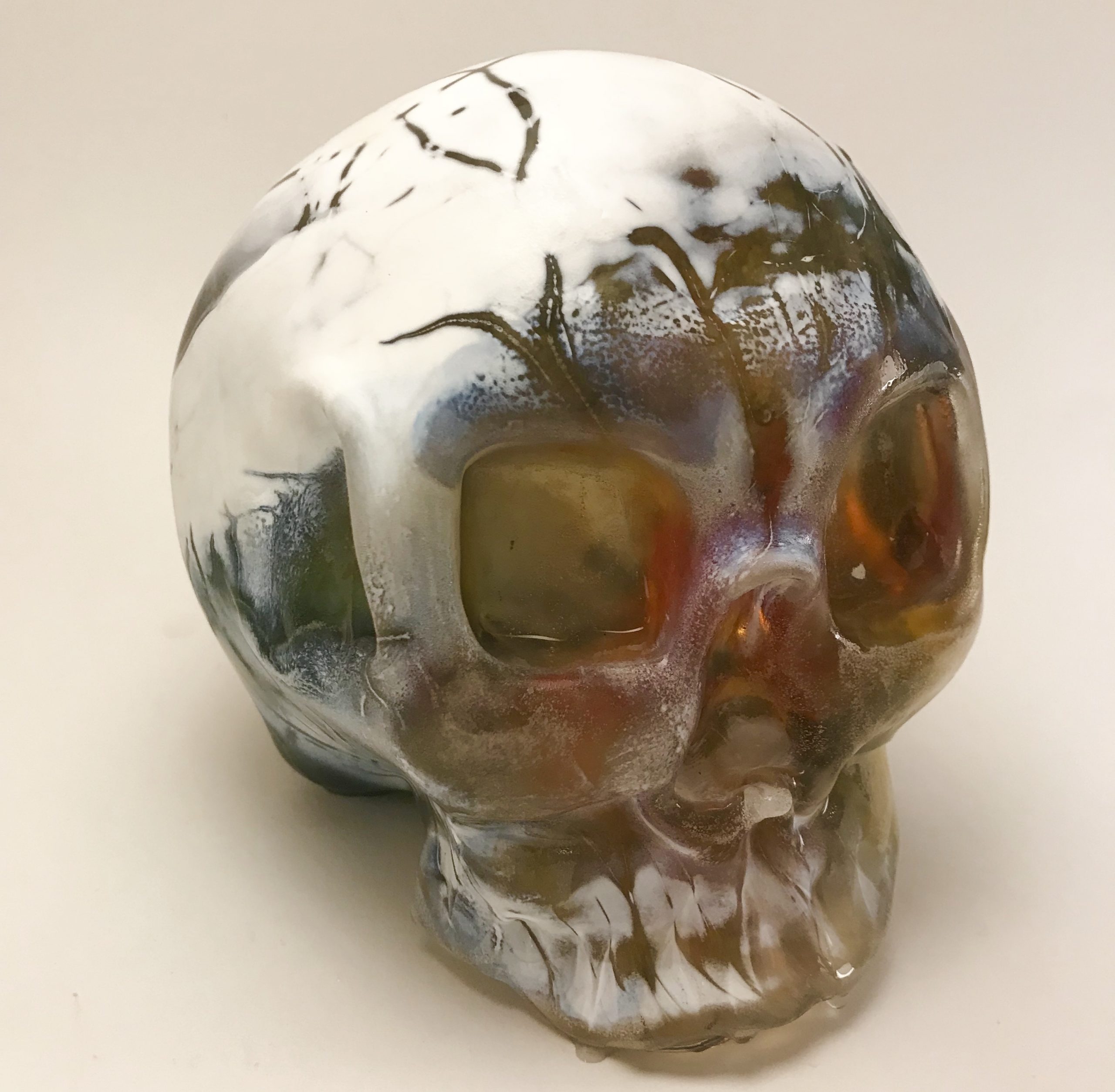 Glass sculpture of skull with cracked white exterior and rainbow interior
